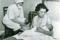 District nurse bathing baby with the mother at home - 1951