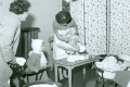 District nurse weighing child at health clinic - 1950s